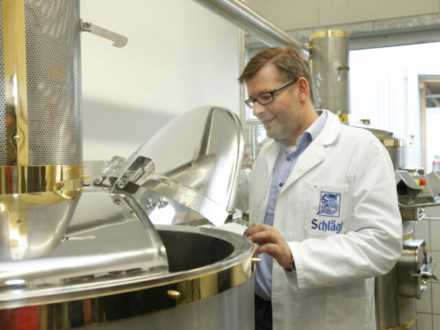 Braumeister arbeitet in der Kreativbrauerei und sieht in einen Sudkessel.