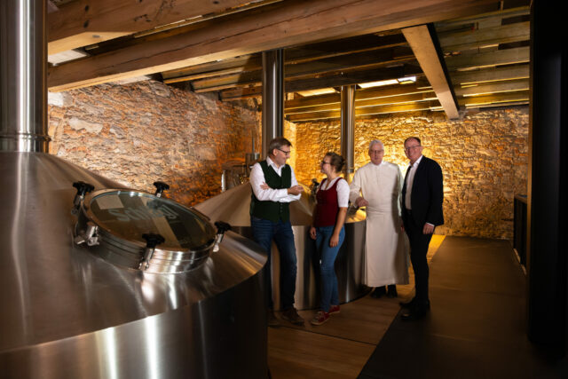 Auf dem Bild sieht man die Braumeister, den Kämmerer und den Wirtschaftsdirektor im neuen Sudhaus neben den Sudgefäßen.